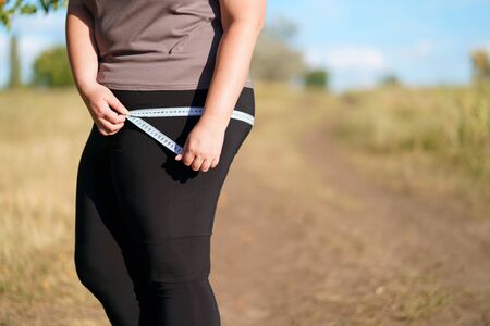 Overweight woman measuring hips with measure tapeの写真素材