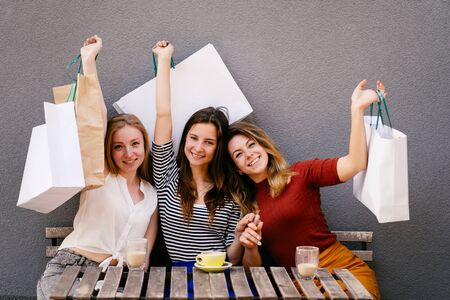 Beautiful girls with many shopping bags in hands smiling and talking outdoorsの写真素材