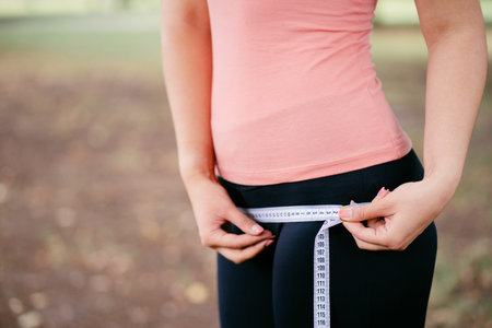 Woman with slim body measuring her waistlineの写真素材