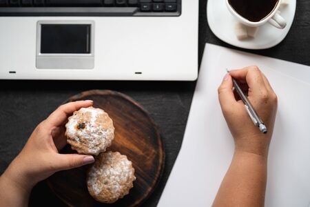 Woman eating muffin at workplaceの写真素材