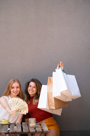 Happy women with dollar bills and shopping bags