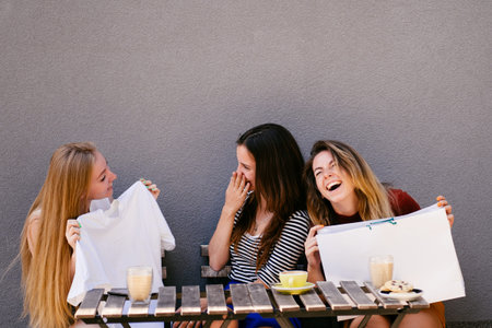 Three friends viewing new clothes after shoppingの写真素材