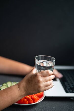 woman working on laptop drinking water from glassの写真素材