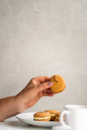 Woman eating cookies and coffee at workplaceの写真素材
