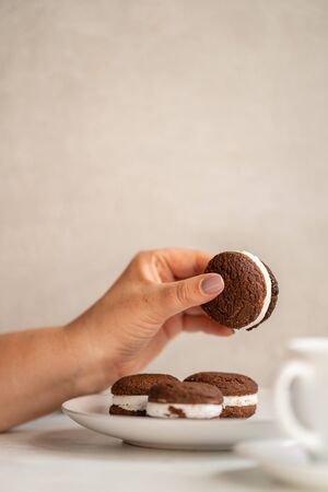 Woman eating cookies and coffee at workplaceの写真素材