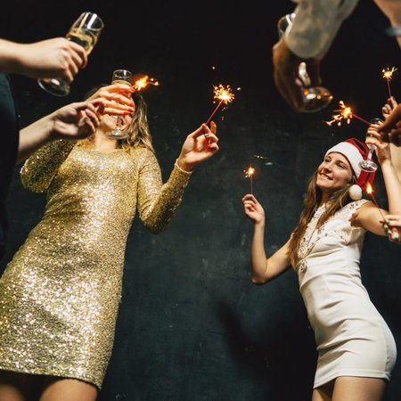 Friends dance with champagne glasses and sparkles