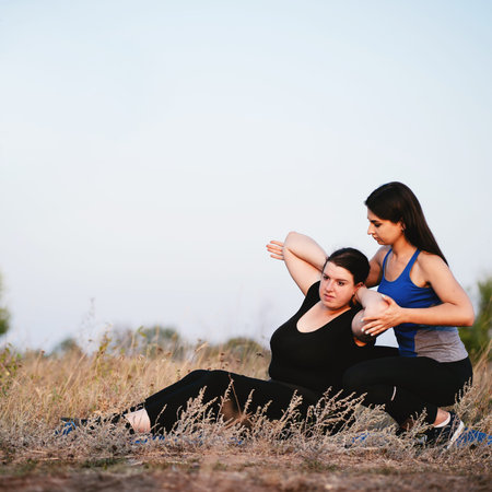 Trainer assisting overweight woman doing sit-upsの写真素材