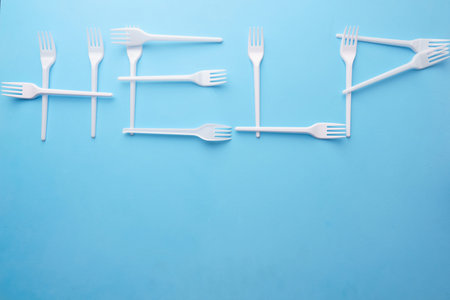 Word Help made of plastic forks on blue