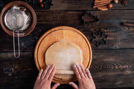 Woman rolling gingerbread dough with rolling pin