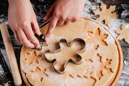 Woman cutting cookies of raw gingerbread doughの写真素材