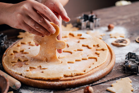 Woman cutting cookies of raw gingerbread dough