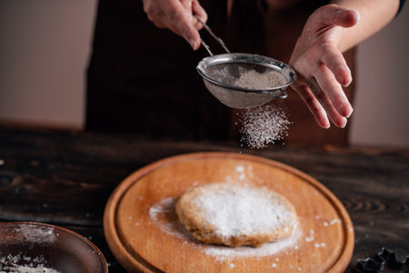 Woman sprinkling flour on gingerbread dough