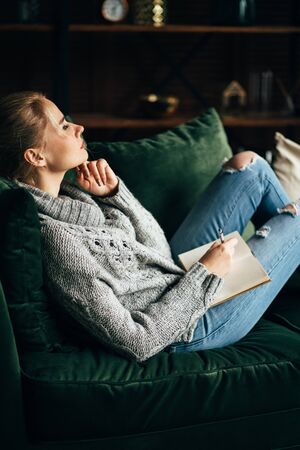 woman relaxing at coach making notes in bookの写真素材
