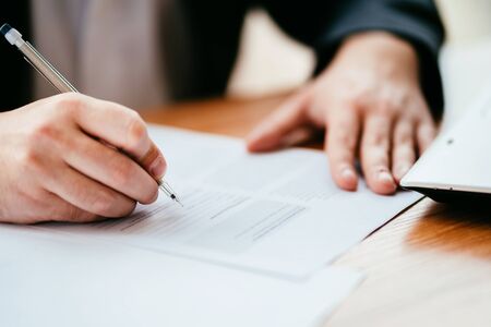 Businessman filling document, signing contractの写真素材