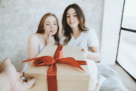 Young women receiving parcel from courier indoors