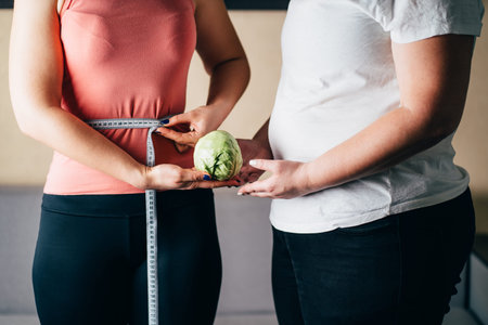 Fit and overweight woman with measure tape