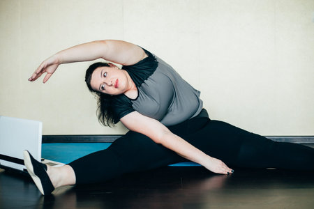 Obese woman stretching watching online workout