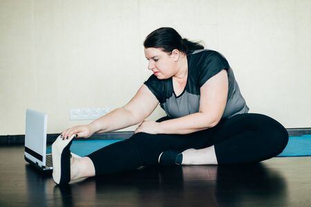 Obese woman stretching watching online workoutの写真素材