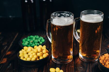 Appetizing snacks with two mugs of light beerの写真素材