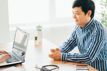 Asian doctor and male patient talking in clinic