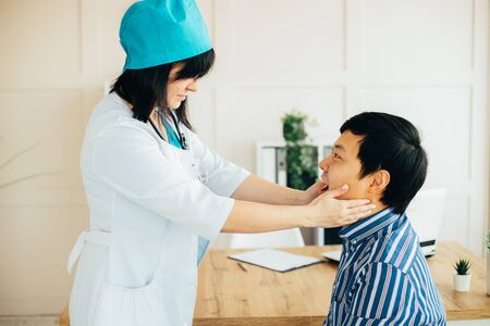 Asian doctor examining male patient in clinicの写真素材
