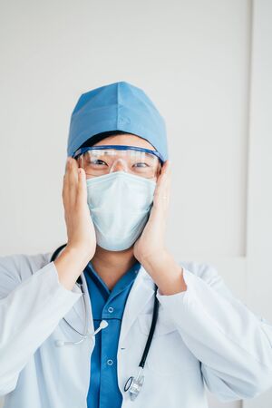 Thrilled asian doctor in medical mask and uniformの写真素材