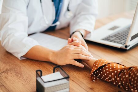 Asian doctor checking pulse of patient in clinicの写真素材