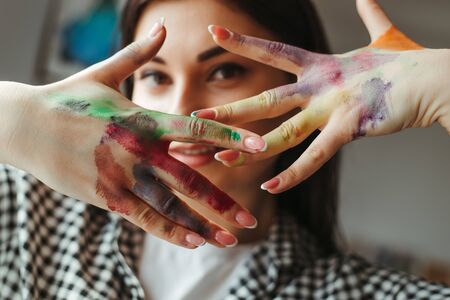 Young talented woman showing hands dirty in paintの写真素材