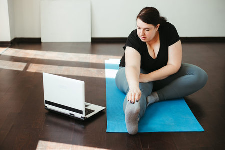 Obese woman doing stretching exercises at home