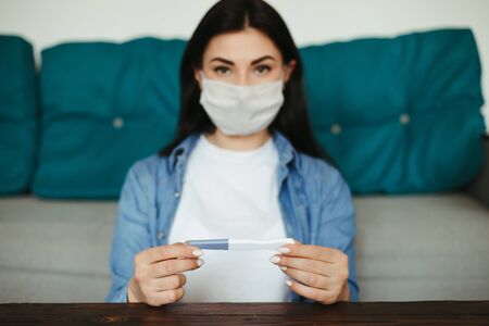 Woman in medical face mask with pregnancy testの写真素材
