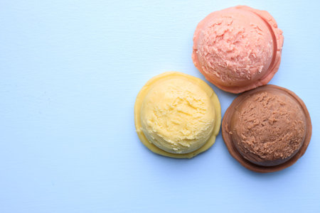 Set of ice cream scoops of different colors and flavors on blue table, copy space. Food background,...