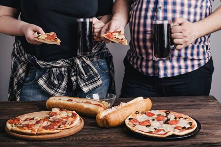 Overweight couple eating pizza and drinking beerの写真素材