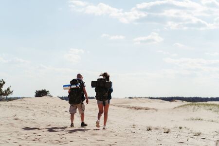Tourists with backpacks traveling through desertの写真素材