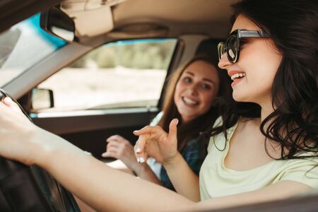 Young women friends having fun traveling by carの写真素材