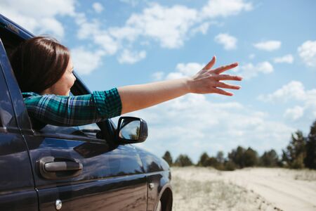 Young joyful woman having fun while traveling by car. Road car trip lifestyle, destination and travel conceptの写真素材