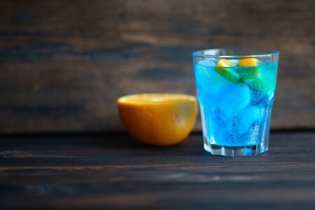 Blue cocktail with orange slice and ice cubesの写真素材