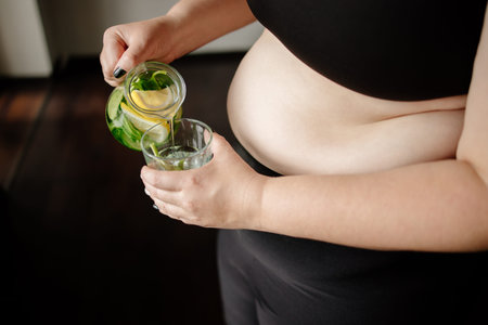 Overweight woman drinking infused water. Detox