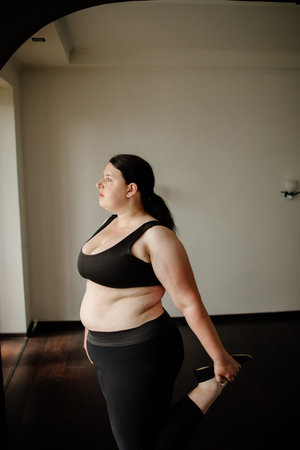 overweight woman stretching legs at home