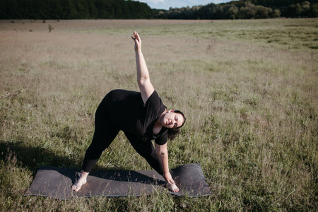 Overweight woman doing outdoor yoga workout