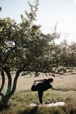 Overweight woman doing yoga exercises in natureの写真素材