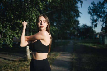 Beautiful sporty woman stretching hands in natureの写真素材