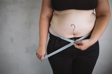 Overweight woman measuring waist with measure tape
