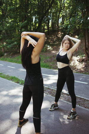 Fit women stretching hands during outdoor training