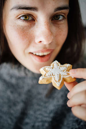 Woman eating Christmas gingerbread, close upの写真素材