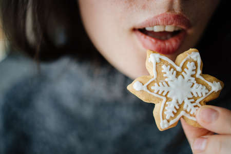 Woman eating Christmas gingerbread, close upの写真素材