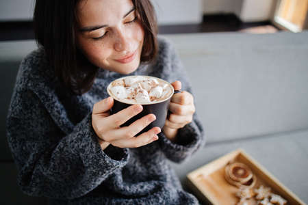 Woman eating festive sweets with hot chocolateの写真素材