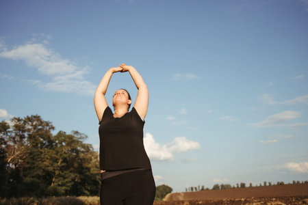 Calm overweight woman doing yoga at summer nature
