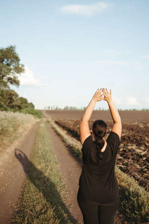overweight woman doing yoga on the country roadの写真素材