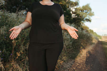 Overweight woman in despair spreading her handsの写真素材