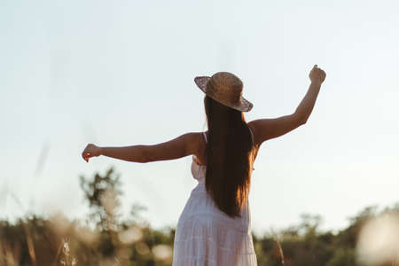 Young carefree happy woman rising hands to the skyの写真素材